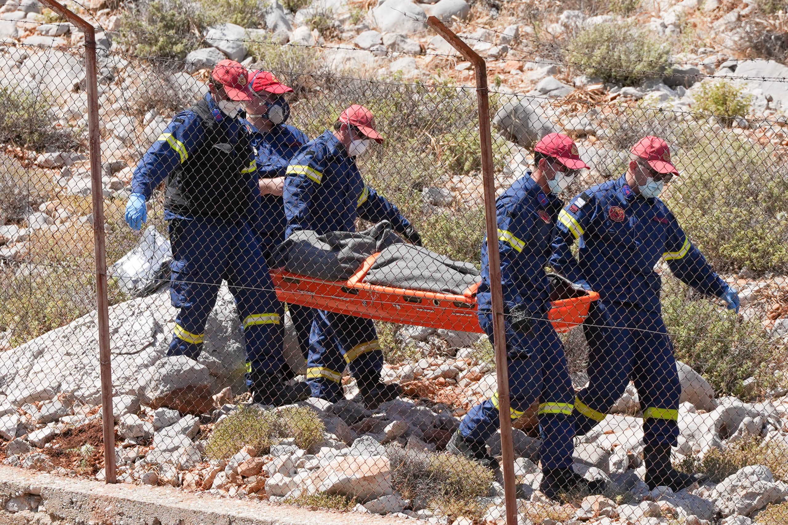 Trabajadores de emergencia con lo que parece ser un cuerpo en una camilla en la isla de Symi, cerca del complejo de Agia Marina, abajo