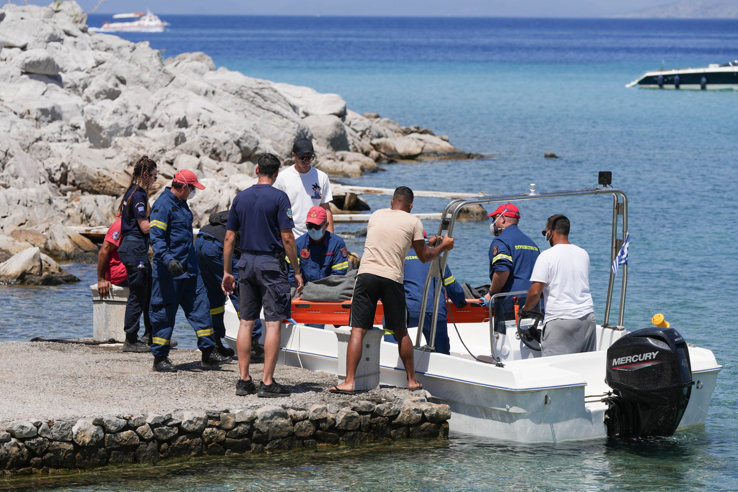 Trabajadores de emergencia cargan la camilla a bordo de un bote pequeño